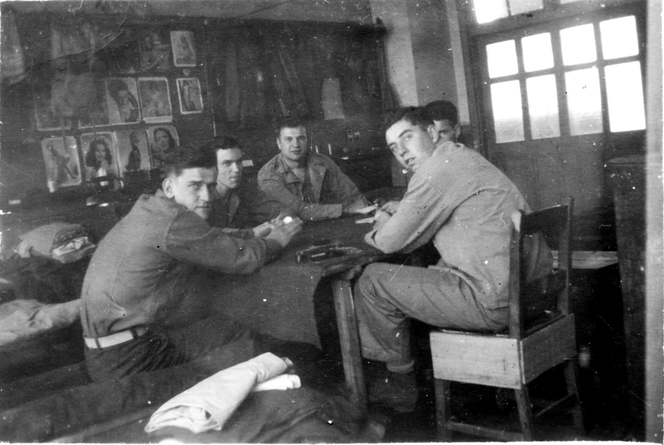 (L-R) Hurlburt, McArdle, Johnson, Kelly, McDonald (Our pinups on blackboard in own room. A pinochle game was in progress)